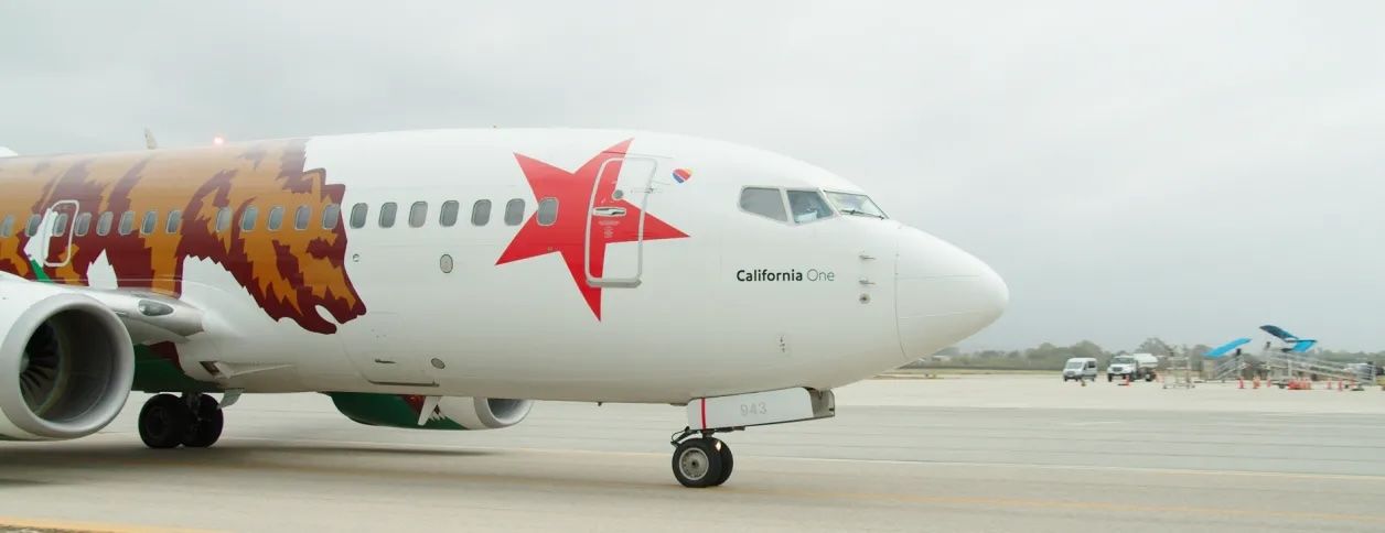An image of a passenger airplane on the runway with the CA state bear and a red star on the side.